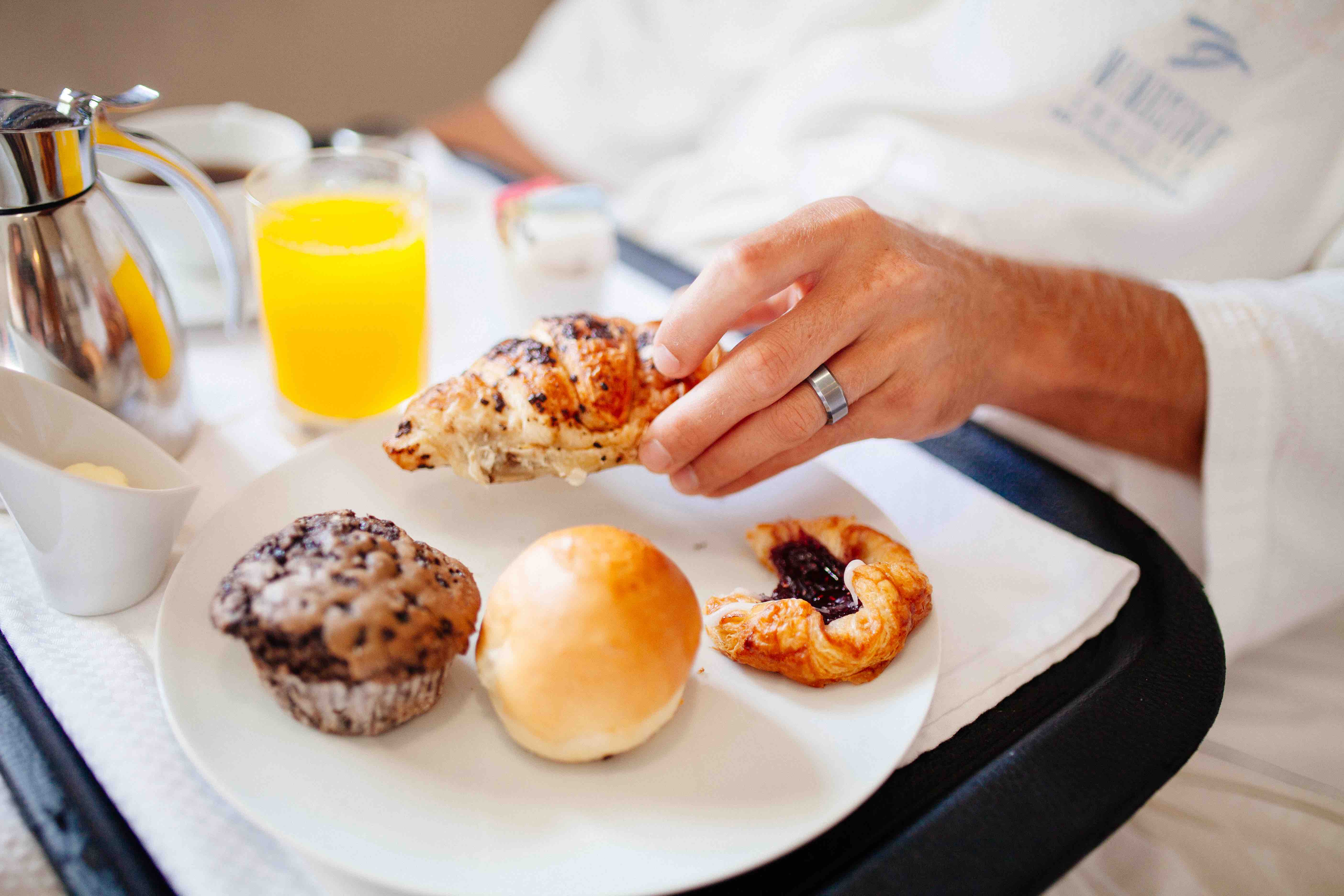 A plate with a chocolate muffin, croissant, roll, and pastry