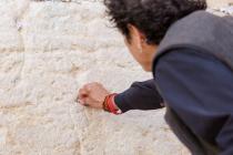 A woman placing a prayer note into the cracks of the Western Wall.